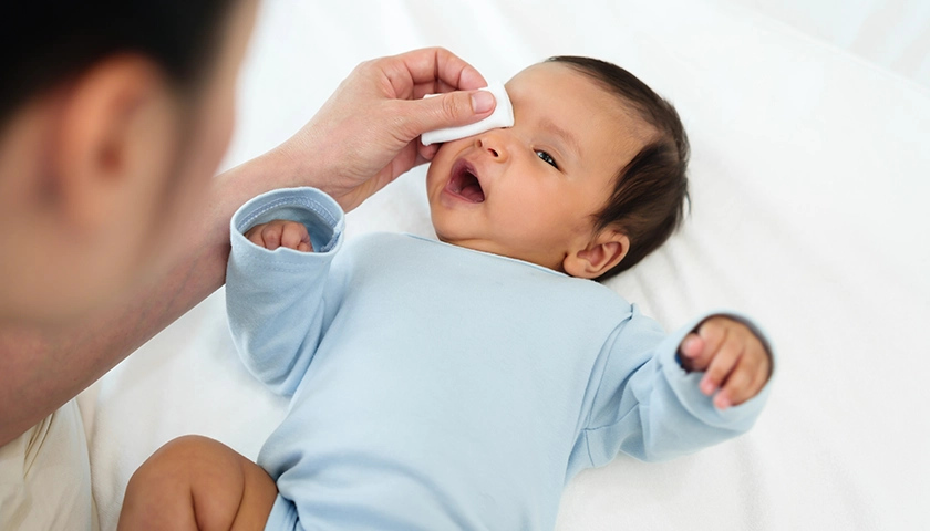 Limpieza del ojo de un recién nacido con suero fisiológico y gasa estéril.webp