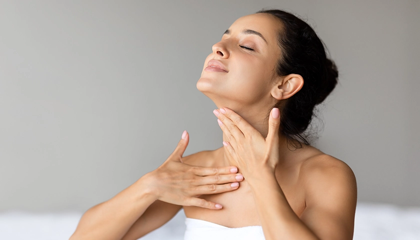 Mujer aplicándose una crema de cuello y escote mediante un masaje ascendente..webp
