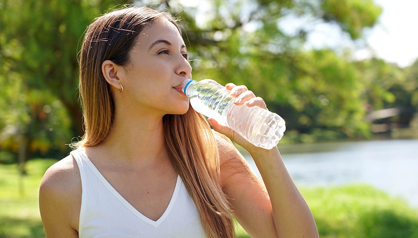 Mujer bebiendo agua para prevenir alteraciones del bienestar urinario.webp