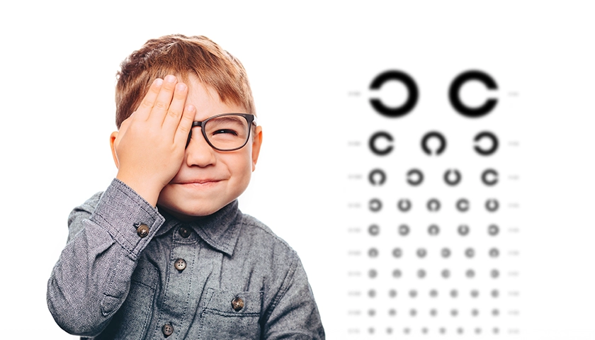 Niño con parche ocular por ambliopía revisando la vista (1).webp