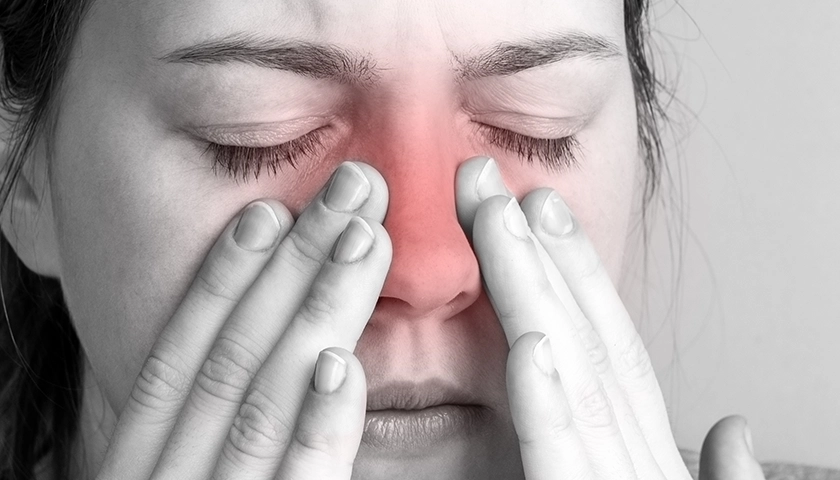 Persona con dolor y presión en la zona nasal, síntoma frecuente de sinusitis.webp