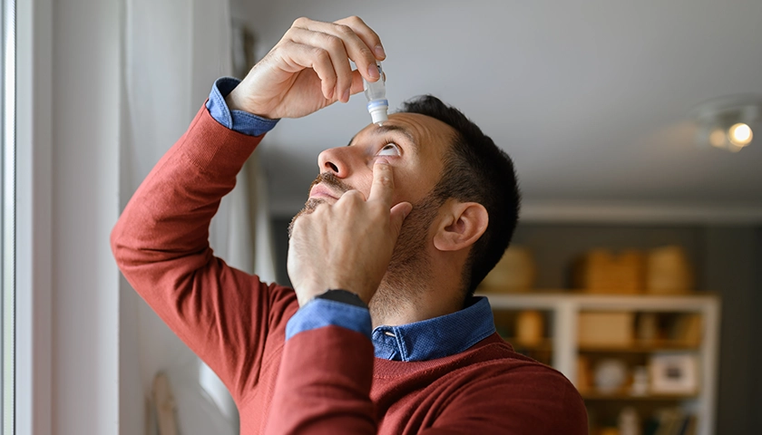 Persona inclinando la cabeza hacia atrás para ponerse gotas en el ojo de forma correcta..webp
