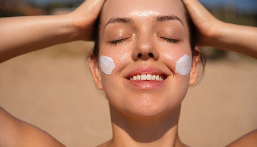 Primer plano de mujer sonriente bajo el sol con manchas de protector solar en las mejillas.webp